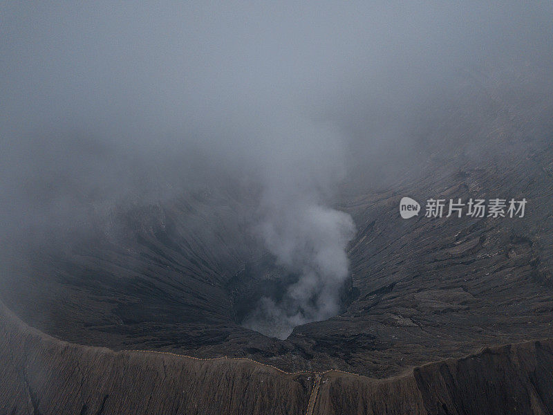 无人机鸟瞰图的Bromo火山口边缘与蒸汽在Bromo山国家公园在Cemoro Lawang村-东爪哇，印度尼西亚，亚洲。旅游目的地冒险的自然概念